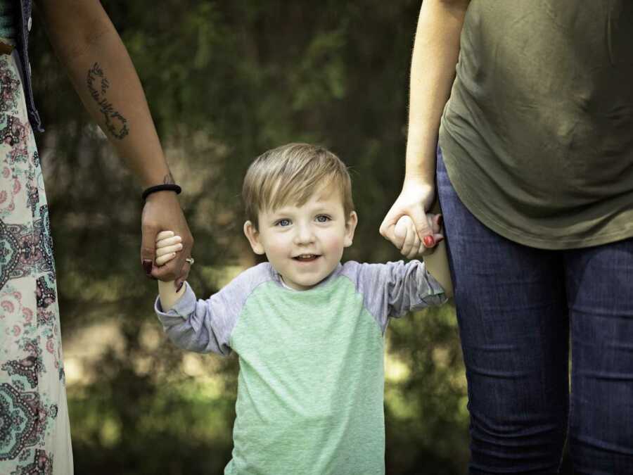 boy holds the hands of his mom and the mom of his heart donor