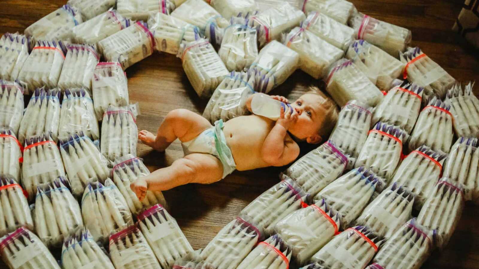 baby sitting with bags of breast milk in heart shape