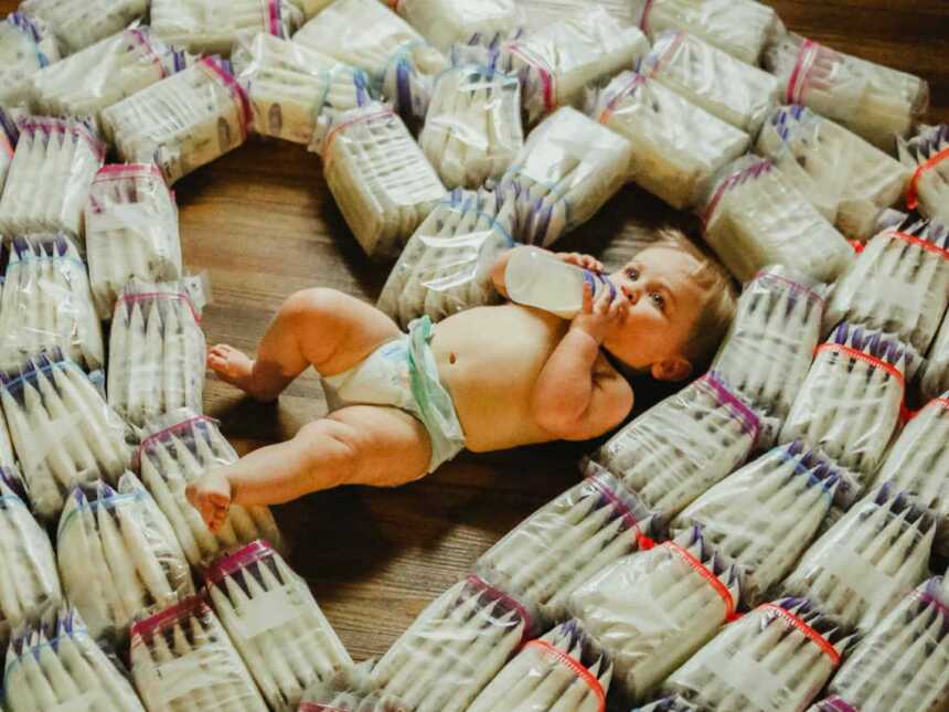 baby sitting with bags of breast milk in heart shape