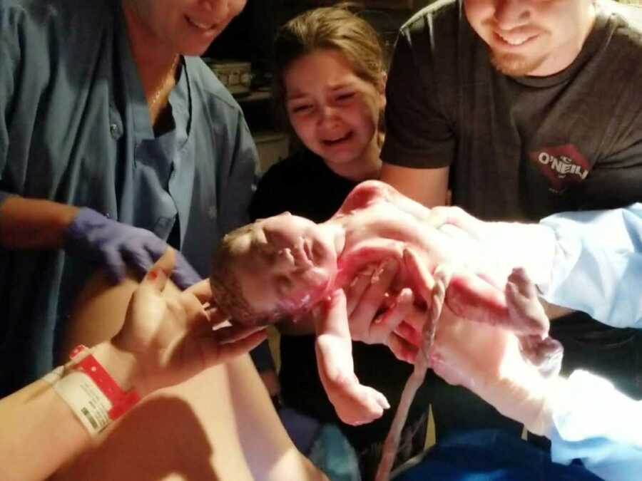 big sister and father help deliver baby with help of midwife