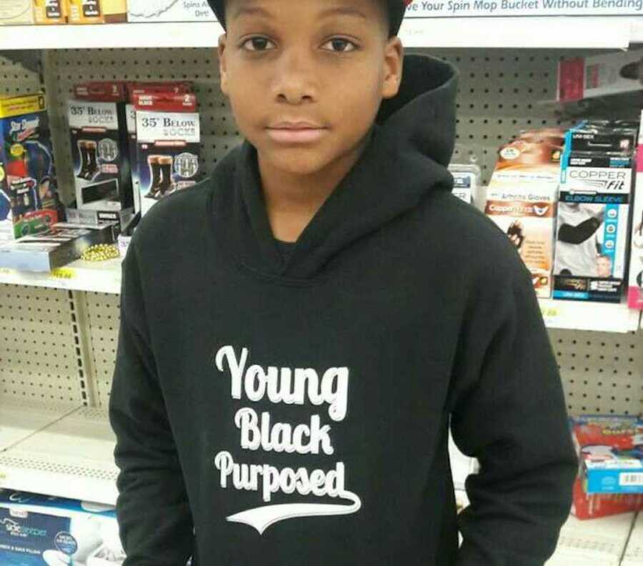 Young black boy wearing a black hoodie that reads "young black purposed"