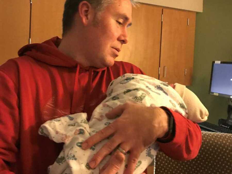 Adoptive father holds newborn daughter in hospital room