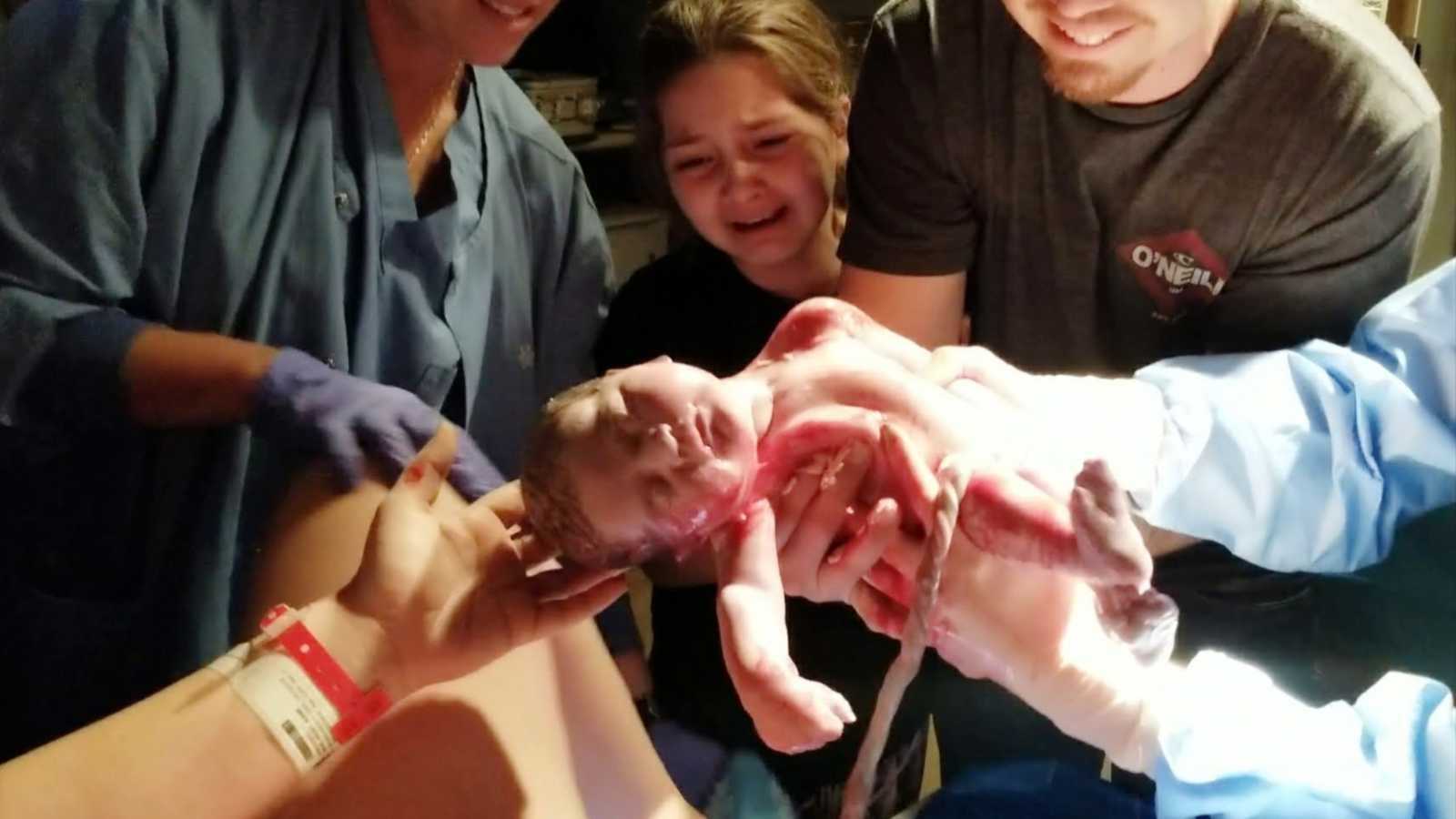 big sister and father help deliver baby with help of midwife