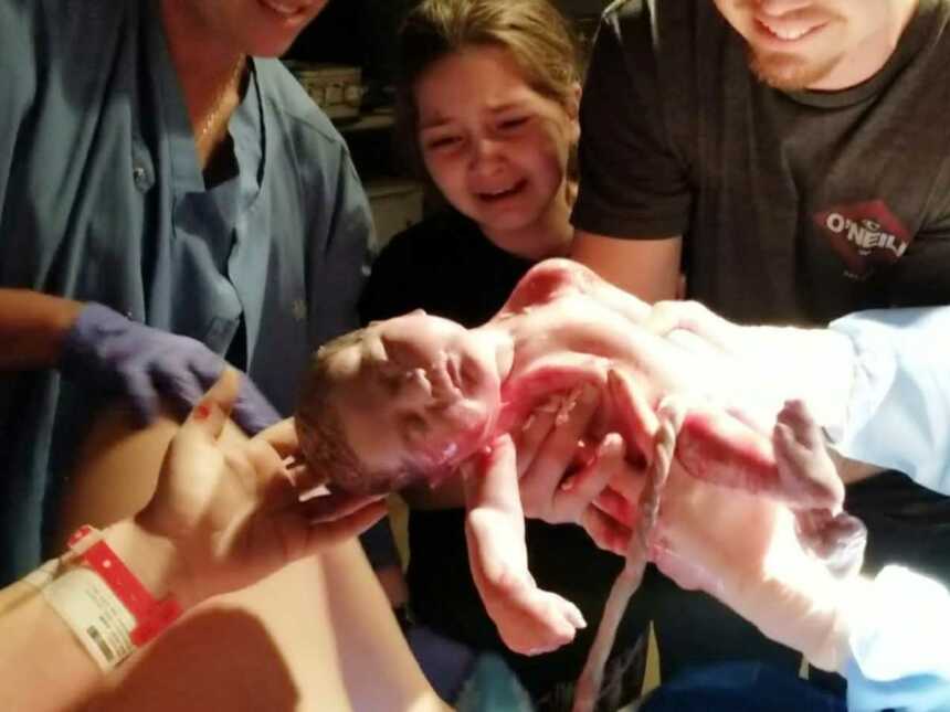 big sister and father help deliver baby with help of midwife
