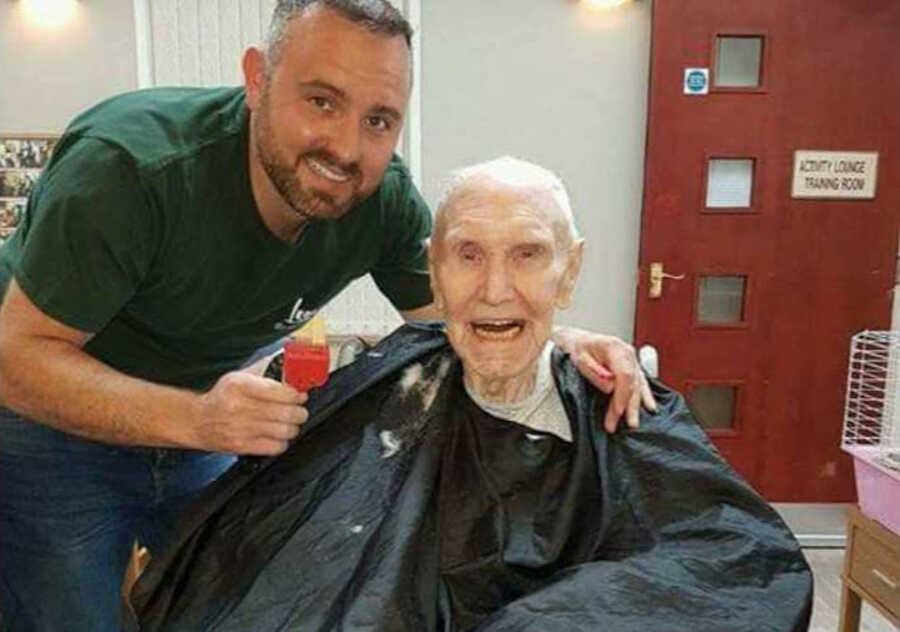 Elderly man with dementia smiling as he gets haircut by barber 