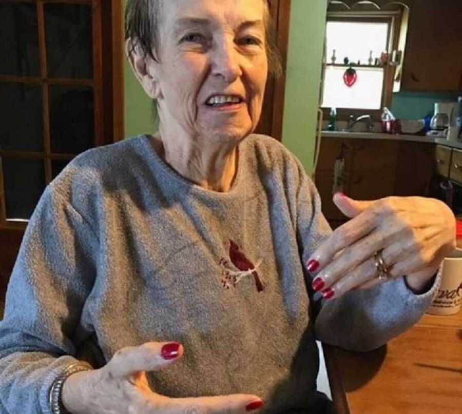 elderly woman with alzheimers is sitting at a table in her house smiling