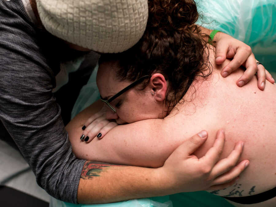 Husband holding pregnant wife in birthing pool