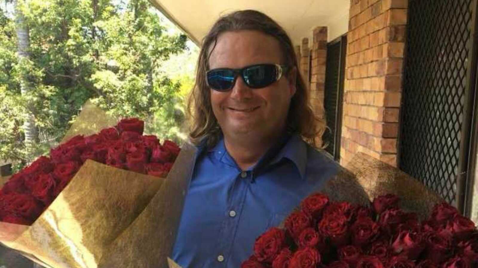 Homeless man holding bouquets of roses