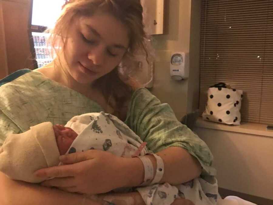 New mother holding newborn in hospital gown