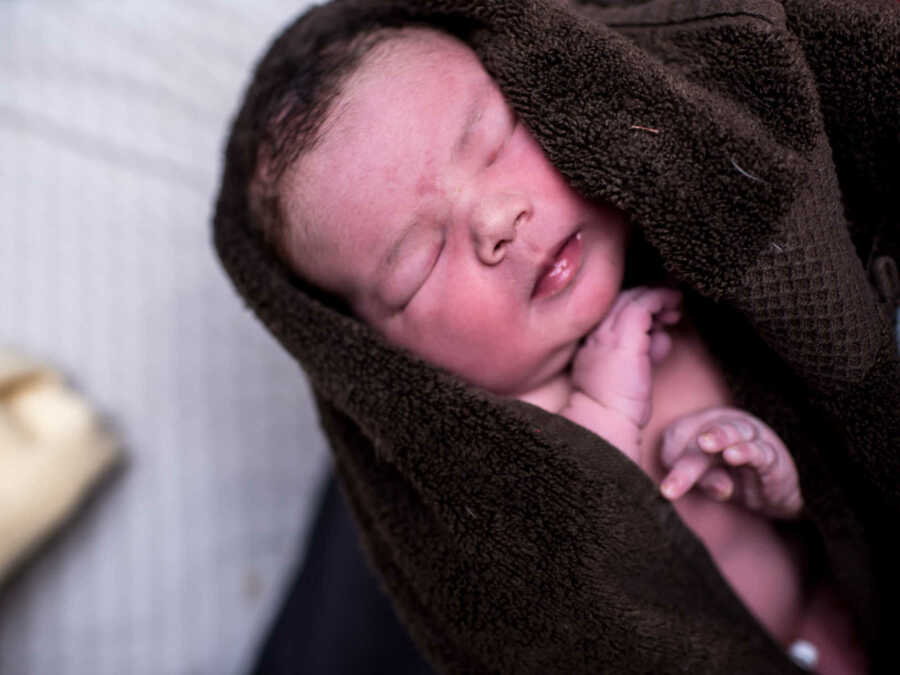 Close up of 11 pound newborn swaddled in brown towel