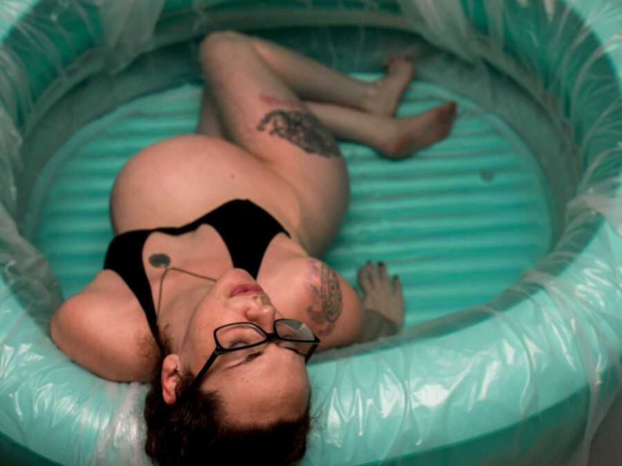 Woman leaning leaning against edge of birthing pool