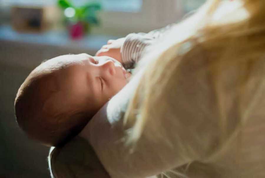 Sleeping newborn baby being held with sun beaming on her face