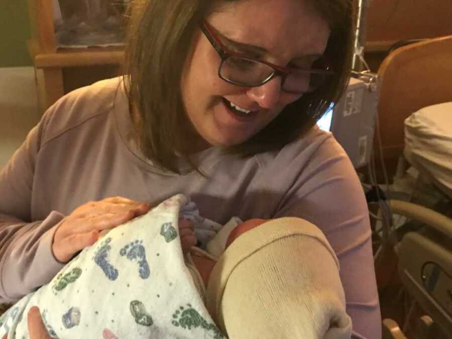 Smiling adoptive mom holding newborn daughter 