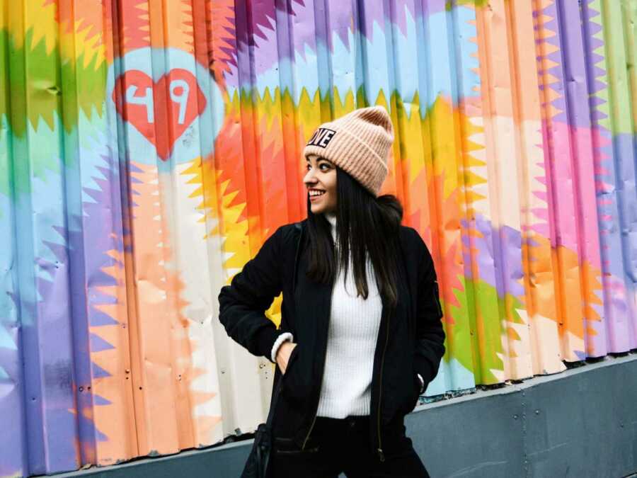 teen girl smiling in front of colorful mural