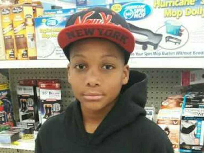 Young black boy wearing a red and black New York hat and a black hoodie