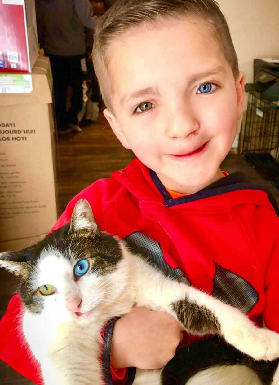 Boy with one blue eye and one green eye holding matching cat