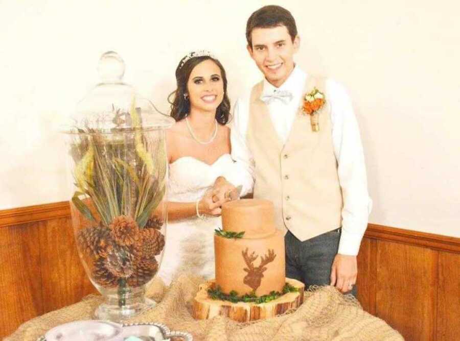 Smiling bride and groom cut orange wedding cake at reception