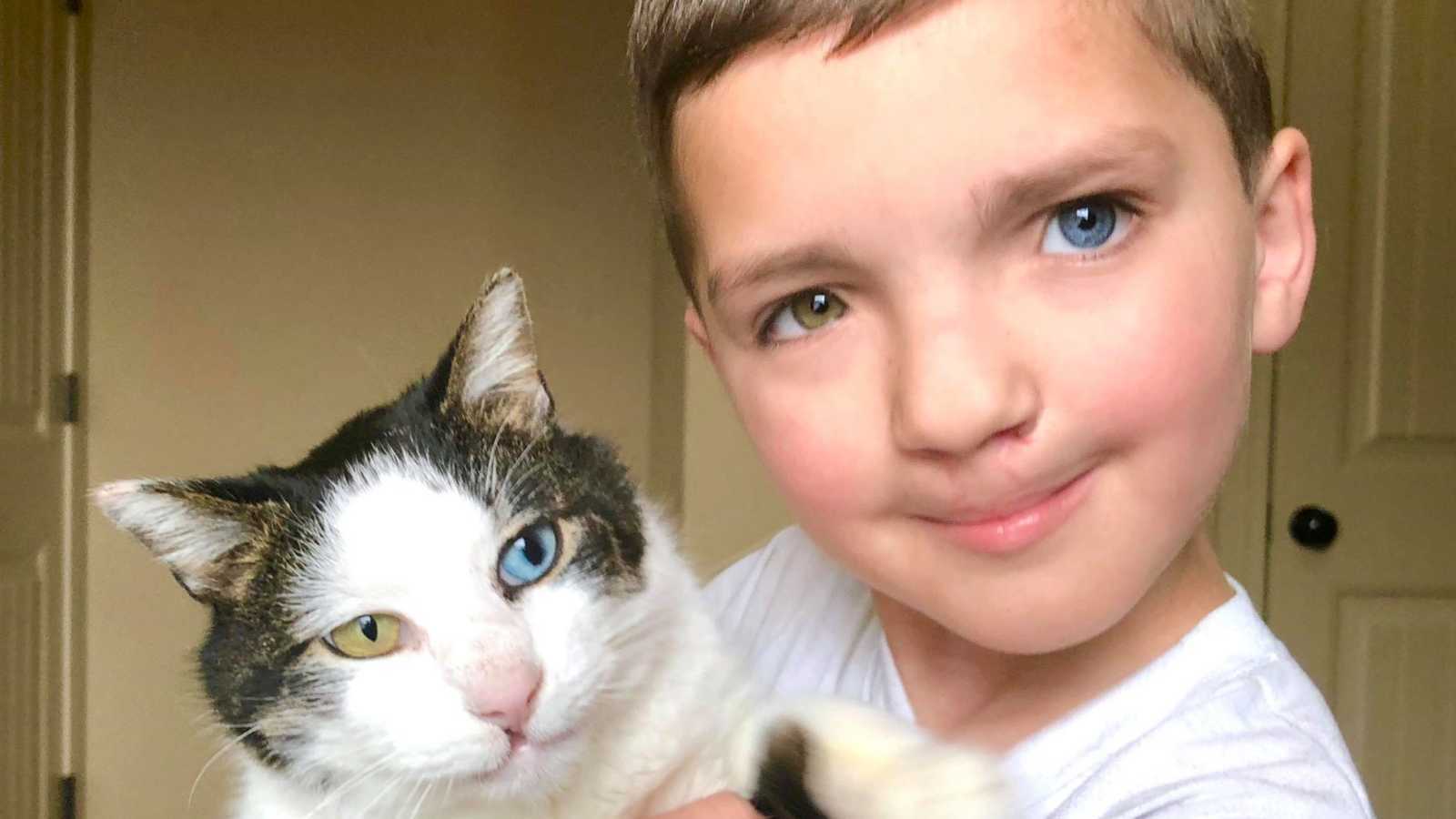 Little boy with heterochromia iridum holding cat