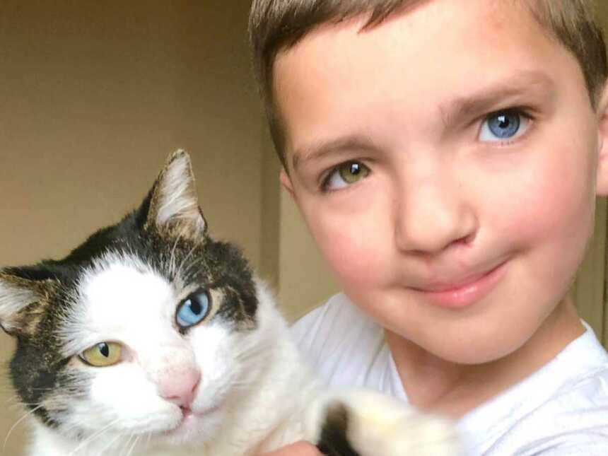 Little boy with heterochromia iridum holding cat
