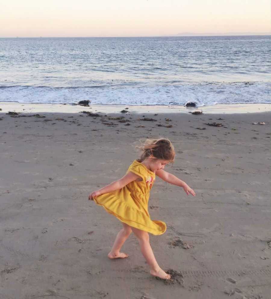 Little girl in yellow dress playing in wet sand