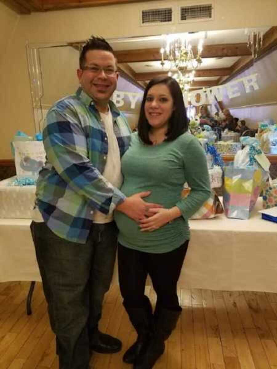 man holds pregnant wife's stomach at baby shower