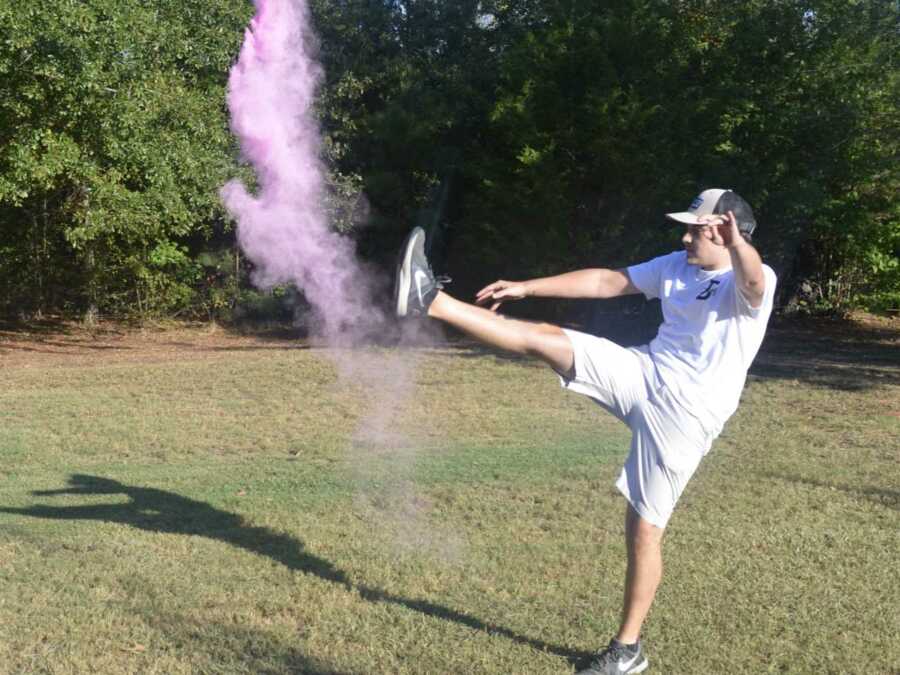 Dad in white outfit kicks open gender reveal in grassy field