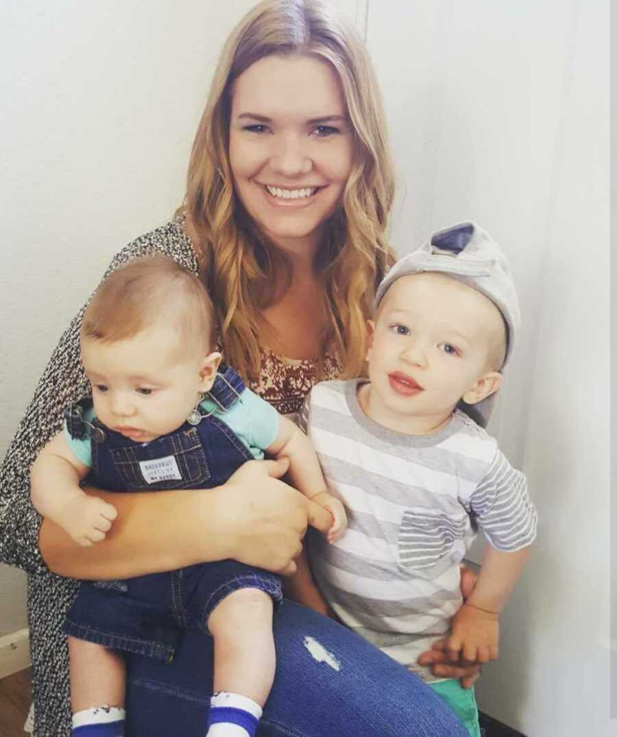 mom smiles while holding two sons