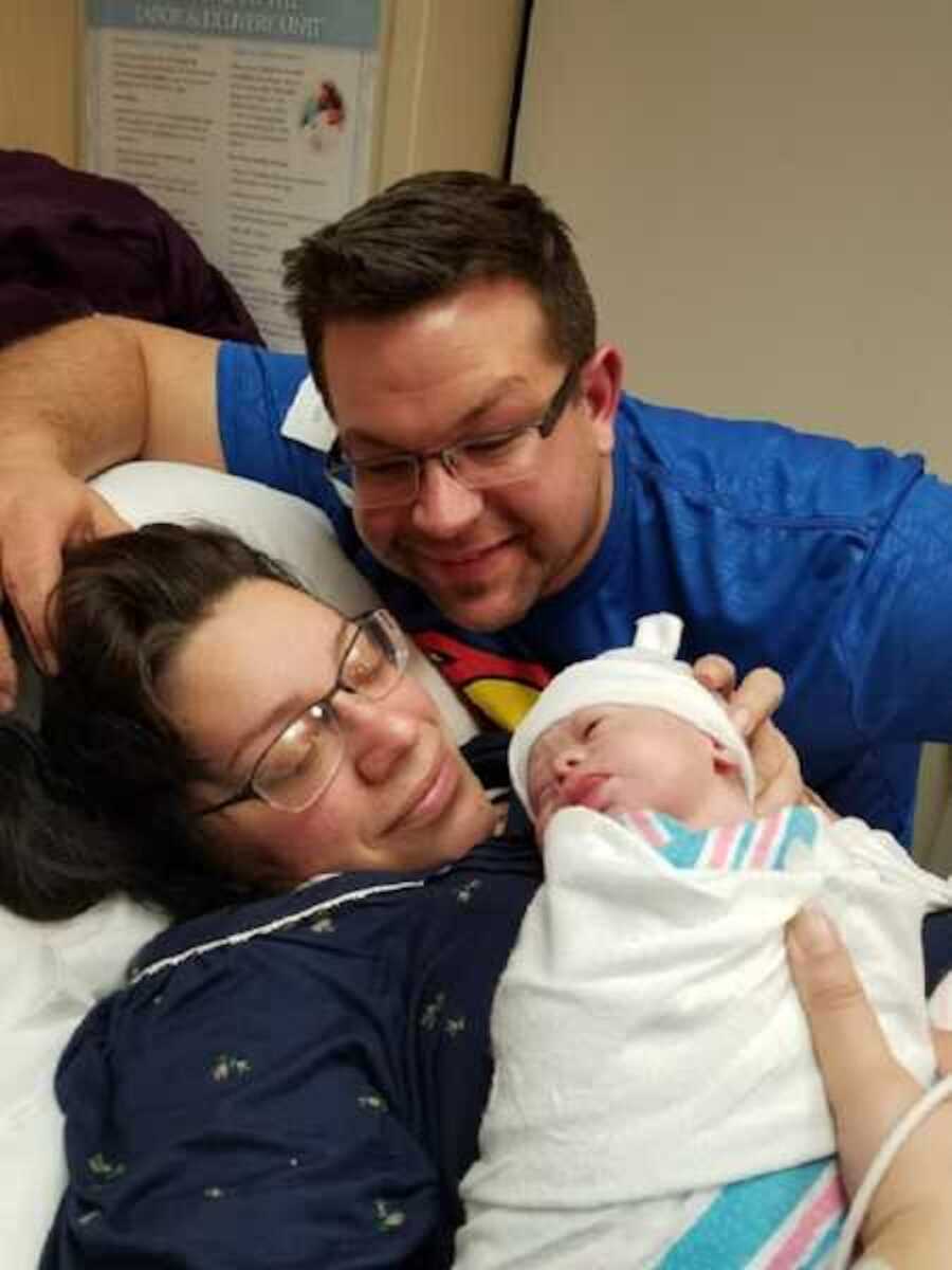 parents holding newborn baby with down syndrome in hospital