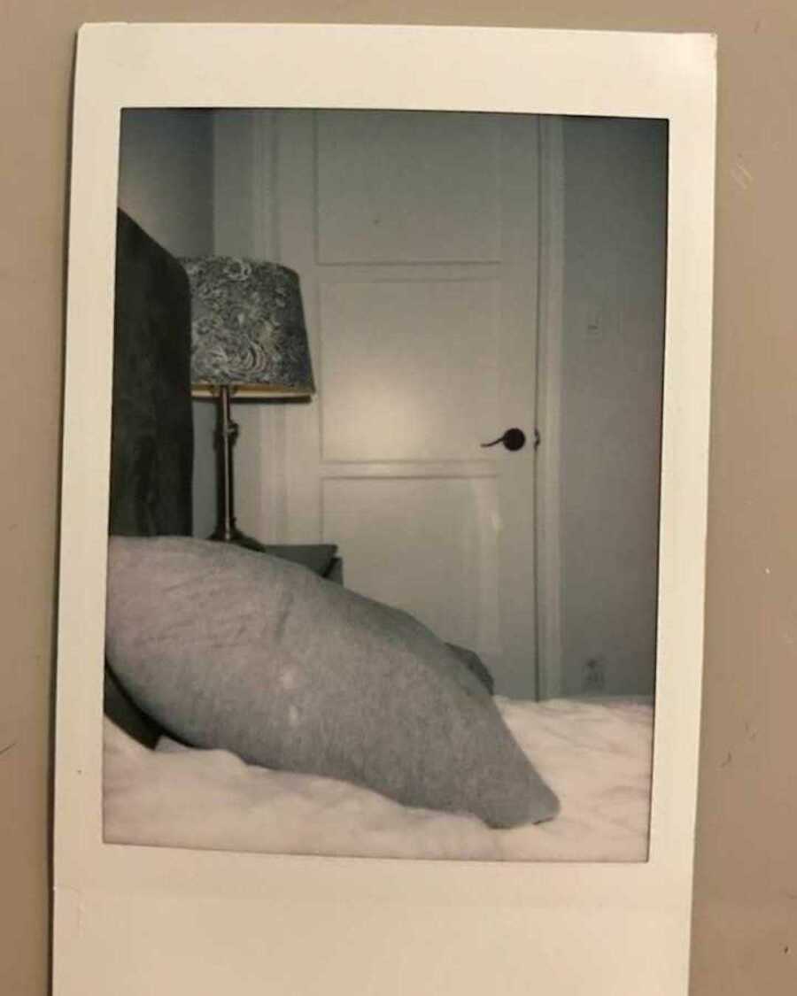 Polaroid of bed with grey pillow