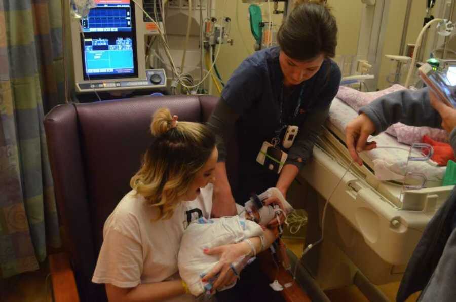 Mother holds newborn two pound baby in NICU while nurse tends to her