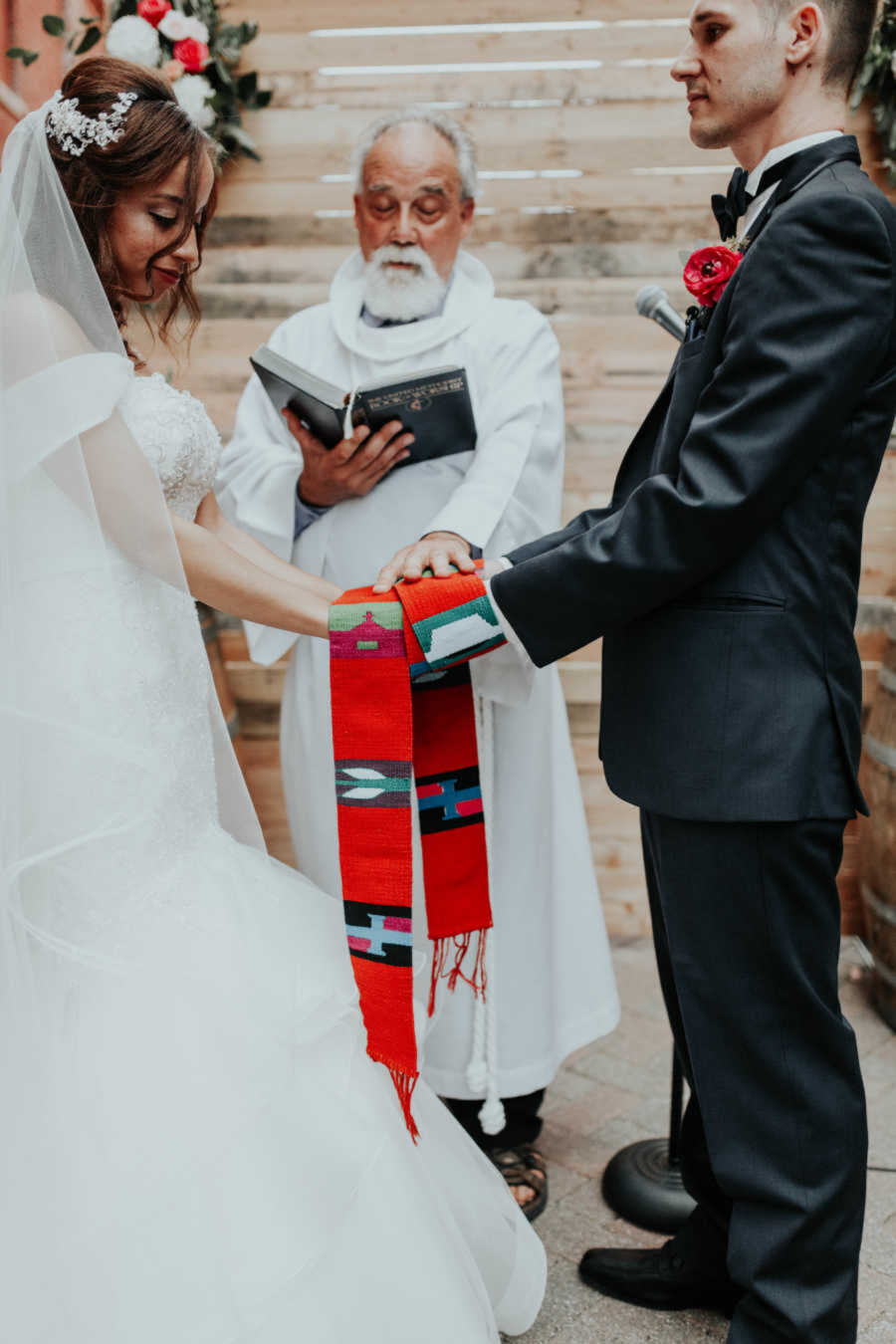 Bride and groom standing at the altar with bride's stepdad who is officiating