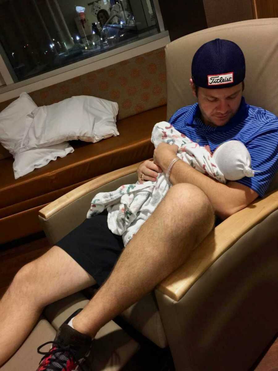 Husband holding newborn in hospital chair