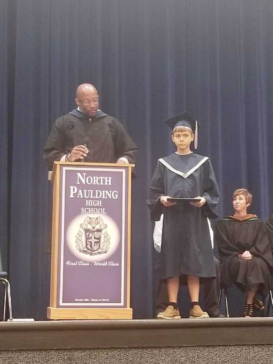 boy with cystic fibrosis on stage getting his diploma at early graduation ceremony