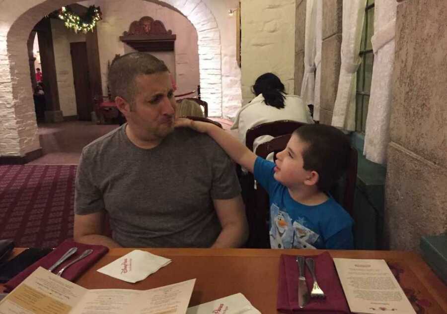special needs dad sits at dinner at restaurant next to non-verbal autistic son