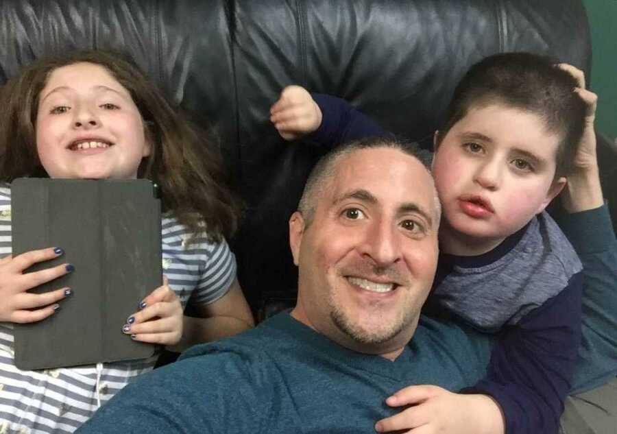 Father sitting on chair smiling with his daughter and non-verbal autistic son