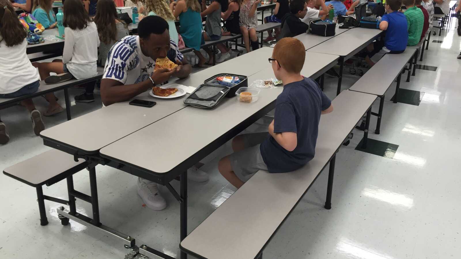 football player sits with boy with autism