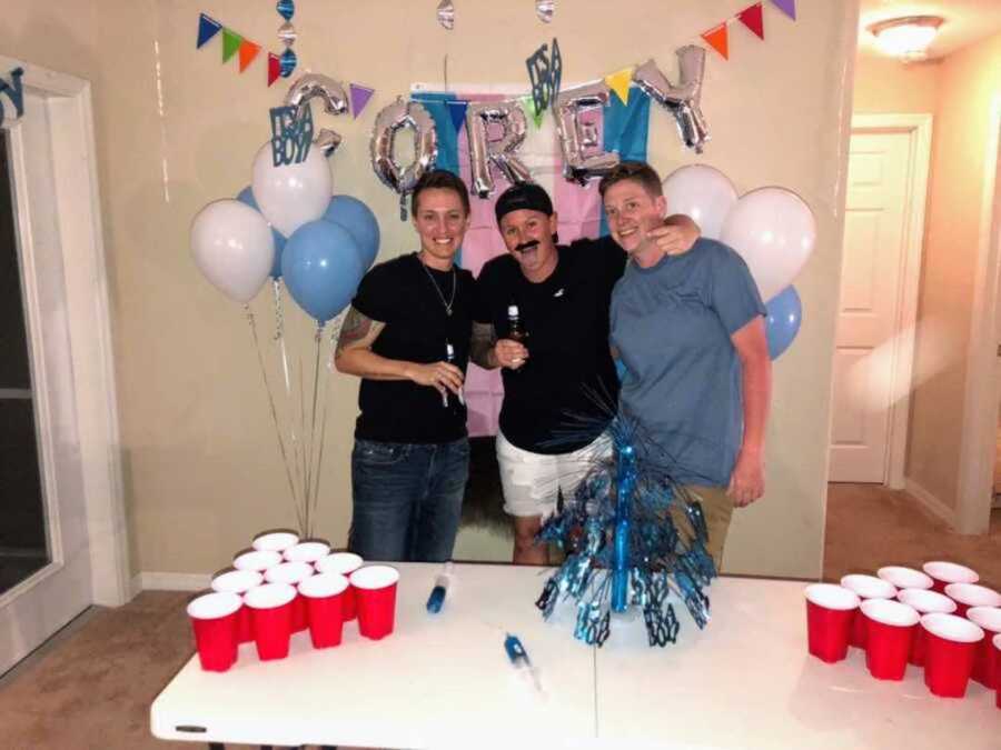 friends standing at gender reveal party for trans man