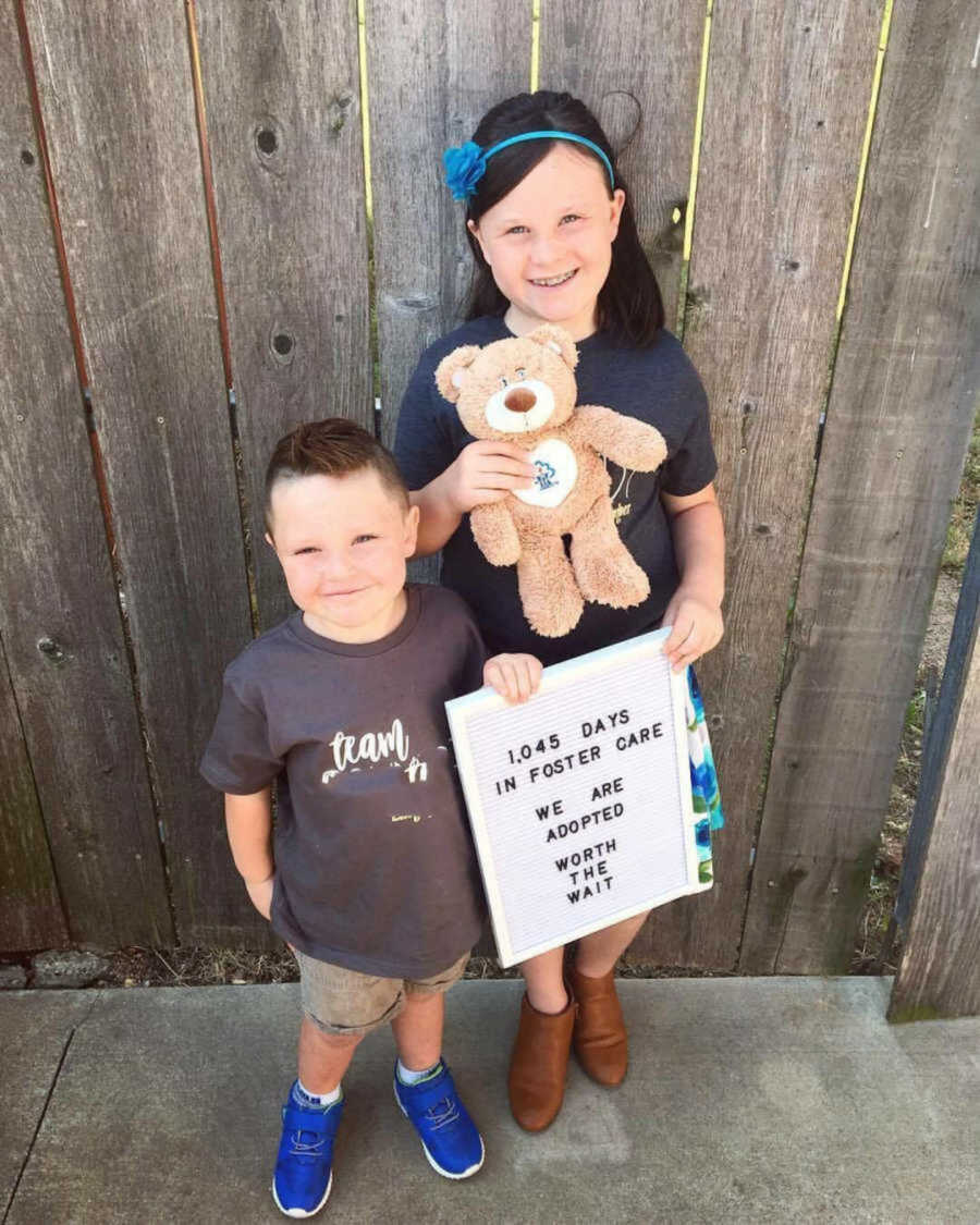 siblings from foster care holding a sign acknowledging their adoption day