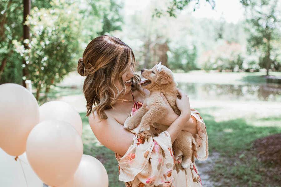 wife holds new surprise golden retriever puppy in puppy reveal