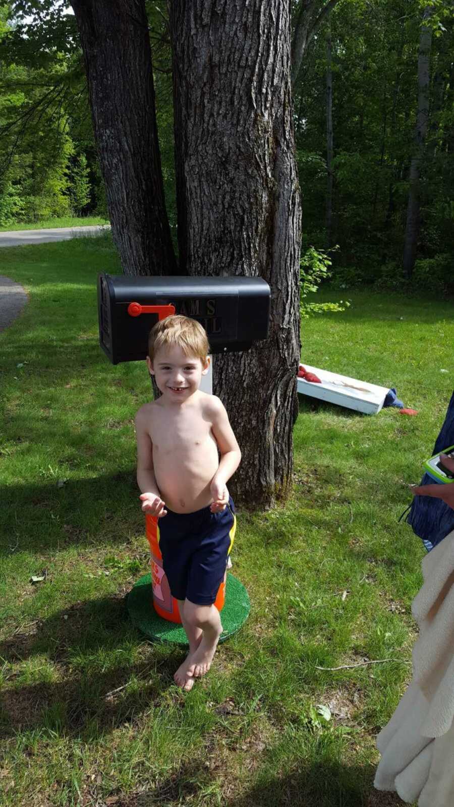boy with autism stands shirtless in front of mailbox made by Home Depot employees