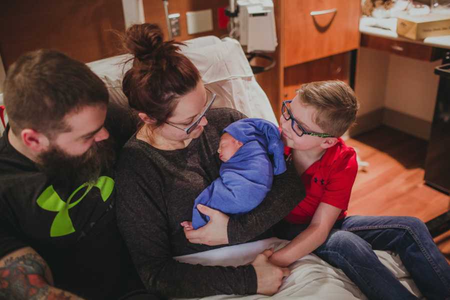 Family surrounds newborn baby boy in hospital bed while they soak up every moment with him