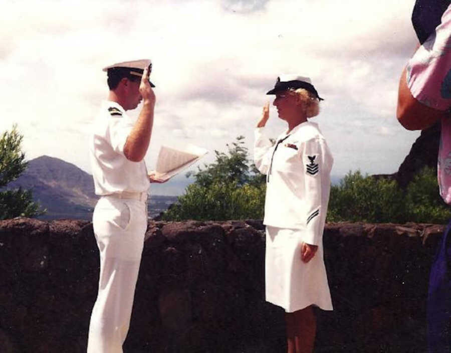 Two Navy soldiers in white uniforms saluting to one another 