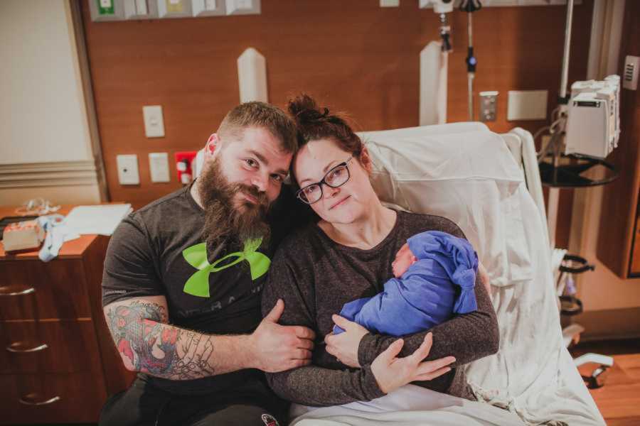 Mom and dad smile in hospital bed as she holds her newborn son