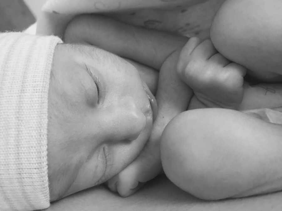 Newborn baby boy in fetal position with beanie on