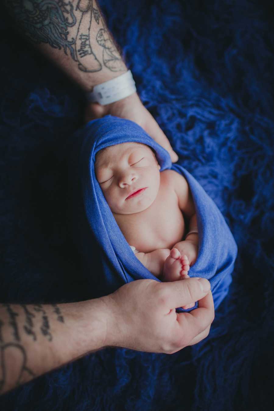 Newborn wrapped in blue blanket sleeping