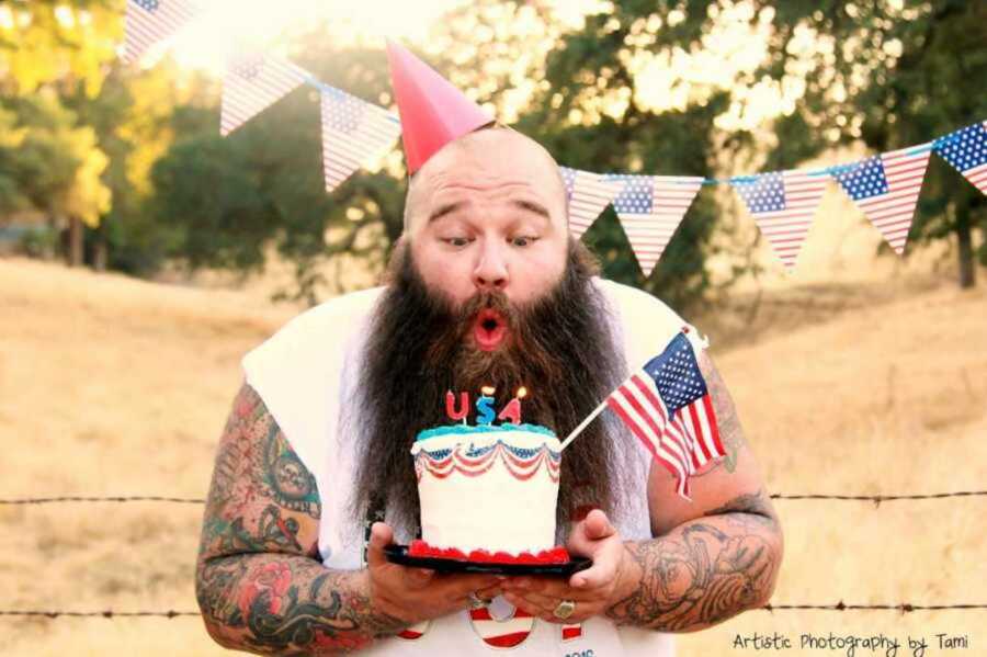 Patriotic bearded man blowing out USA candles 
