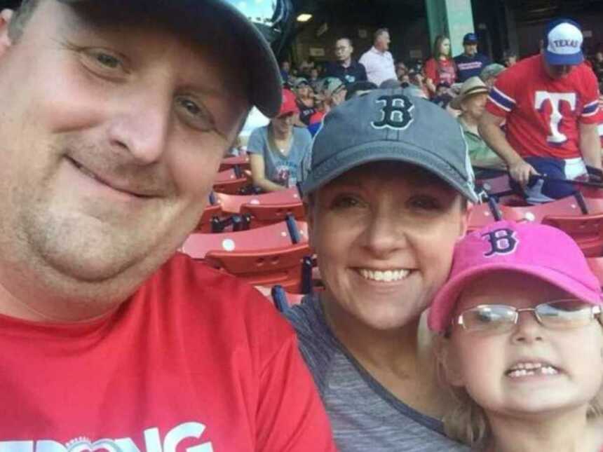 Mom and dad sit with their daughter at a Boston Red Sox game