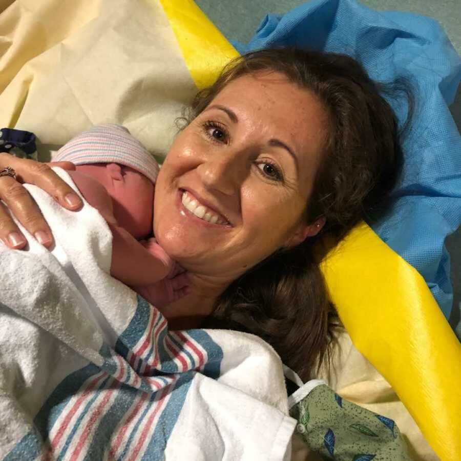 Postpartum mom embracing newborn in hospital
