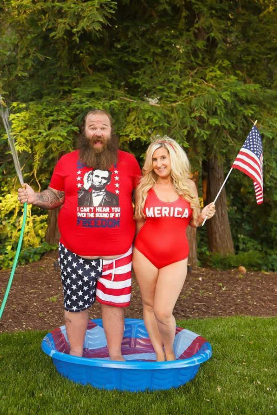 Patriotic couple smiling in kiddie pool holding American flags