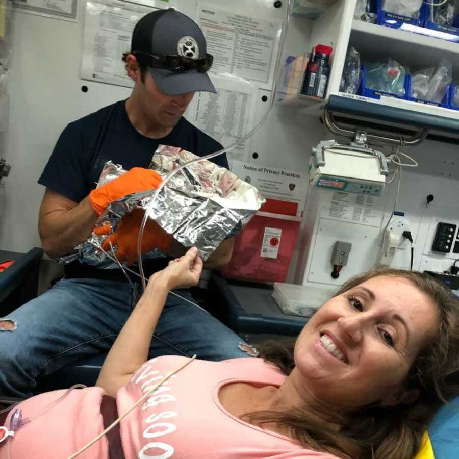 Mom smiles in ambulance alongside husband and newborn